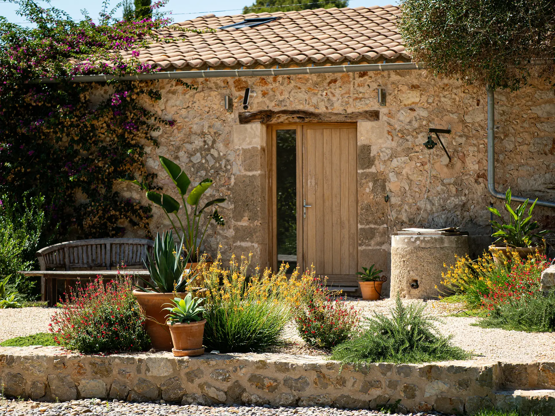 Mallorcan stone building with terracotta pots of succulents and herbs on a gravel terrace.
