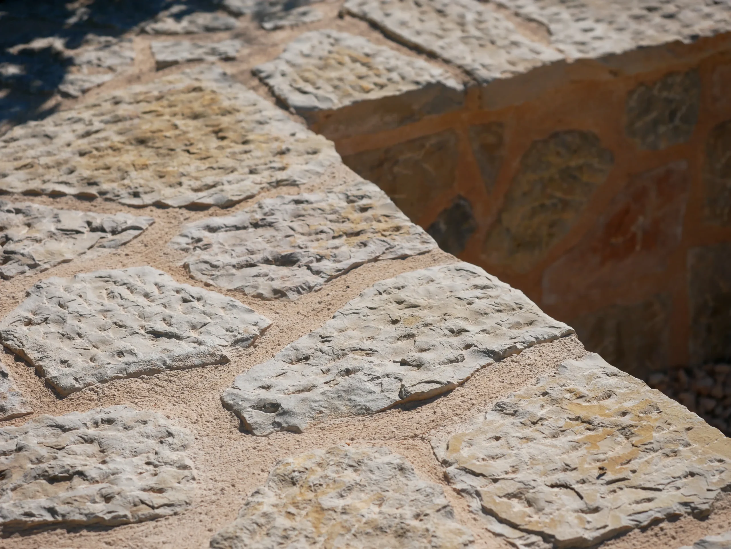 Close-up of dry-laid stone wall built with rough-cut limestone and sand joints.